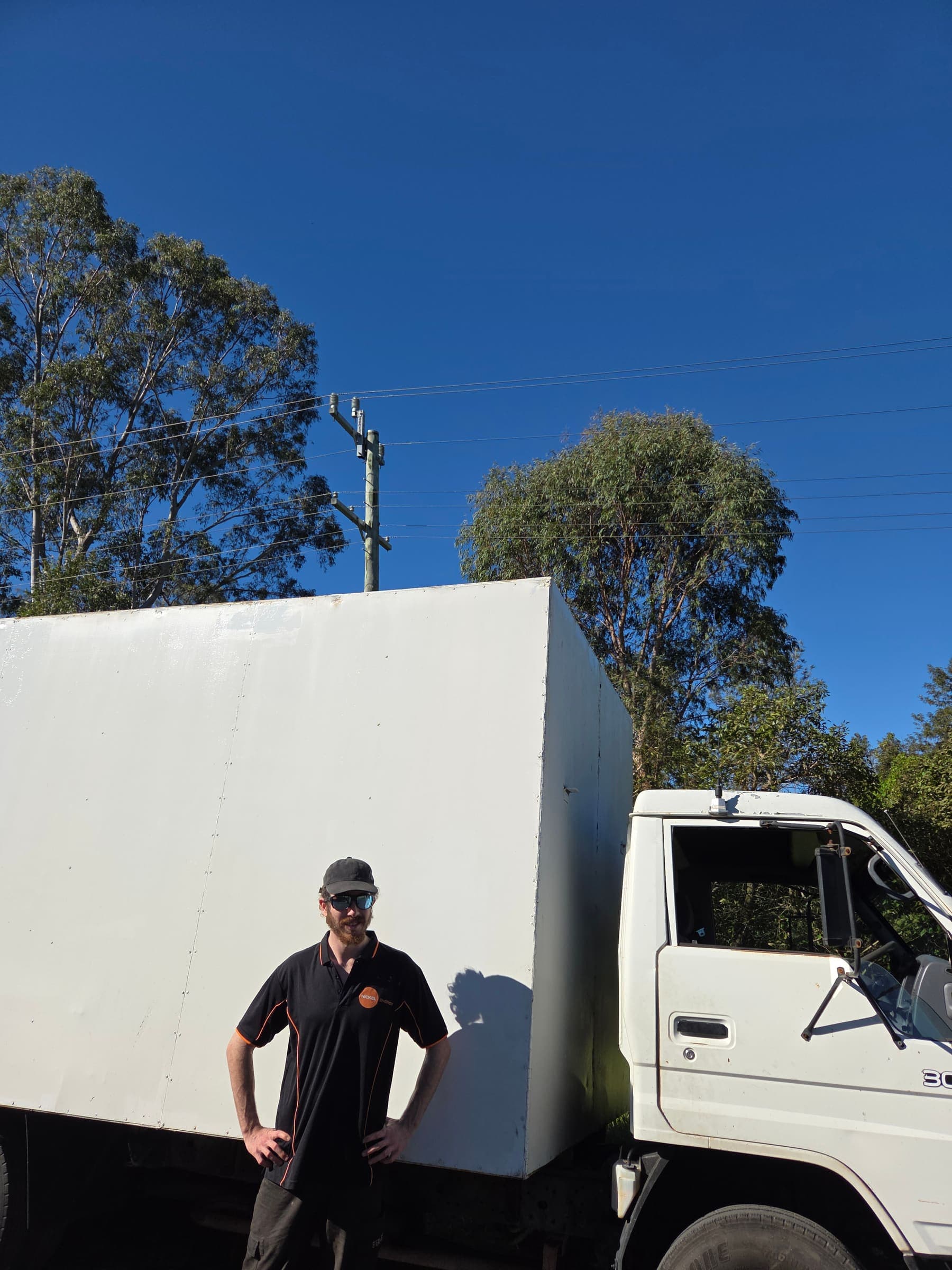 Side of the white box truck with gum trees behind